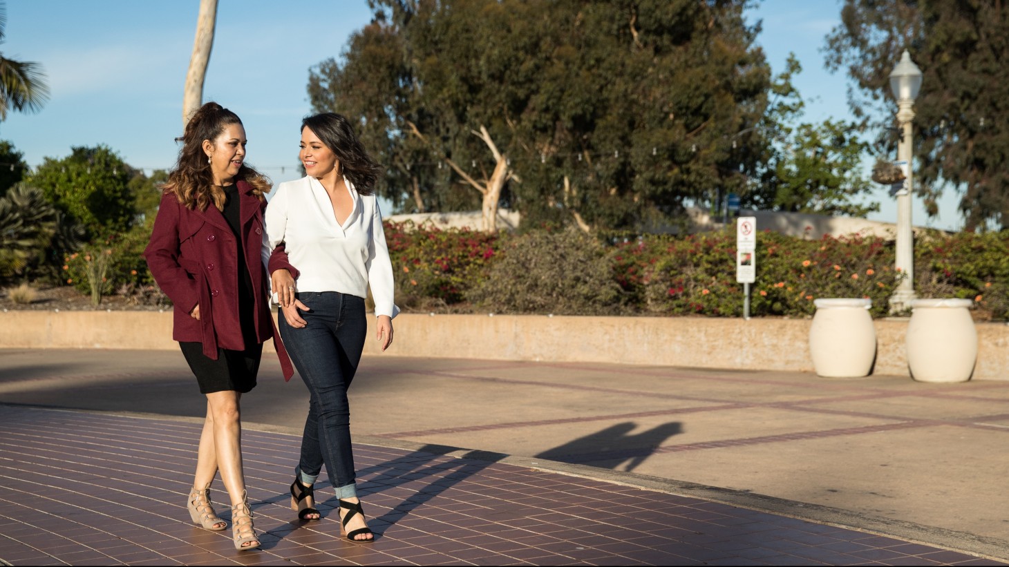 Two women walking arm-in-arm on a sunny day